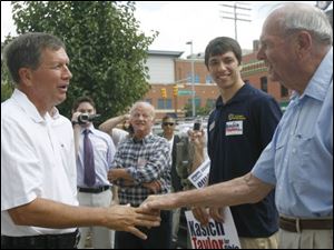 John Kasich, left, shakes hands with Peter Petersen of Toledo in front of the Lucas County GOP headquarters downtown.
