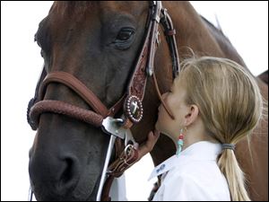 Gracyon Amos, 9, of Wood County gives her quarter horse Poko a kiss before competing in the trail novice class at the Lucas County Fairy.