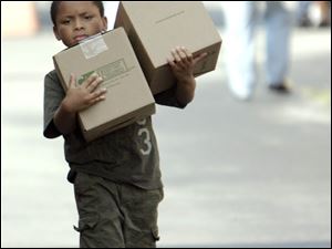 Seth Ward, 7, of Toledo carries boxes from Feed The Children, which distributed food and toiletries at the Erie Street Market.