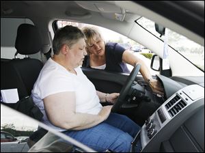 Joan McVicker listens intently as Charlie's Dodge sales representative Carol Gerken leans in to explain some of the features of the Dodge Journey in Maumee.