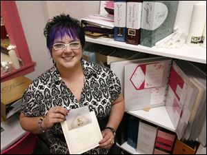 Kelly Heuss, owner of Puttin' on the Glitz inPerrysburg, displays a wedding invitation.