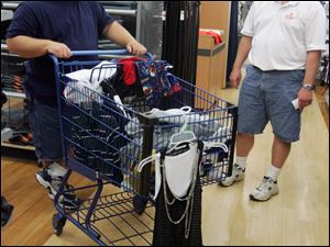 Duane Lender of Millbury, left, stops and chats with his neighbor Scott Swartz while shopping at Meijer in Maumee with gift cards provided for storm victims by area Lions Clubs. The Lender and Swartz families lost their homes in the June 5 tornado.