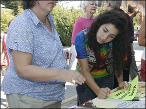 Beverly Elwazani, left, and her daughter Layan Elwazani, 16, both of Bowling Green, sign up to volunteer to help in the effort to pass the levy for the Wood County District Public Library at Monday's rally.