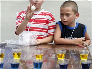 David Arce, 5, watches as his brother Daniel Arce, 7, plays a game that challenges him to toss a Ping-Pong ball into a cup.