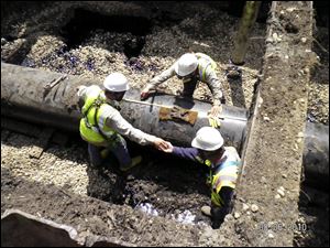 Technicians in protective gear take measurements before cutting and removing a section of the Enbridge pipeline at the site of the July 25 oil spill in Michigan's Calhoun County.
