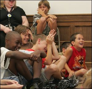 From left, Jeremy Beckley, 11, David Stirn, 11, Nicholas Carr, 9, and Dylan Hershey, 7, all of Toledo, enjoy the magic show at the 75th birthday celebration of the Toledo Heights branch of the Toledo-Lucas County Public Library.