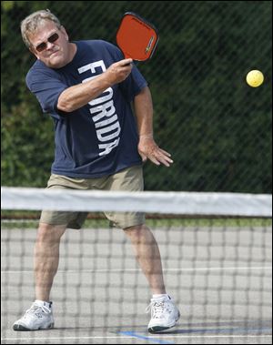 Jeff Foster aims the ball over the net. Pickleball games go to 11 points.