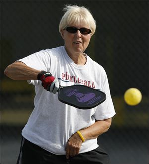 Connie Mierzejewski of Rossford plays at the outdoors Glenwood Courts in Rossford. The game is played with hard, solid-faced paddles and perforated plastic balls.