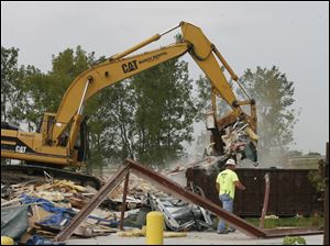CTY demo12p  Shane Garlick operates an excavator to clear the site of the former Lake Township Administration Building. Lonie (cq) Featherstun, next to the dumpster, is sorting metal for recycling, so "we put less in the landfill." The Lake Township Administration Building, damaged by tornadoes on June 5th of this year, is razed to the ground by Klumm Bros. of Swanton, Ohio on August 11, 2010. They are planning to have the site cleared by the end of the day. The Blade/Jetta Fraser