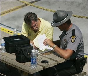 Mark Neal, left, pilot of a Cessna plane that crash landed Friday in Lake Erie off South Bass Island, speaks with Sgt. Eric Short of the Sandusky post of the Ohio Highway Patrol.