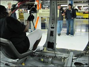 A device known as the Happy Seat, on a moveable robot arm, enables employees of Chrusler's Belvidere, Ill., assembly plant to see where they are attaching air bags inside vehicles.
