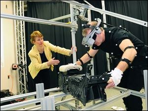 Allison Stephens, an ergonomics engineer at Ford's campus in Dearborn, Mich., monitors her colleague Glenn Harrington, fitted with motion-capture receptors, as he reproduces the movements required to install a center console in a Fusion midsize sedan. 