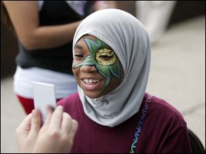 CTY birmingham16p  Sayedah (cq) Rashad (cq), 13, of Toledo, checks out the face painting wotk of Amber Lefever, [not pictured] of Bowling Green, who is holding the mirror for her. The 36th annual Birmingham Ethnic festival, centered in St. Stephen's parish, in east Toledo, Ohio on August 15, 2010.  The Blade/Jetta Fraser
