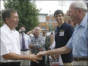 During a trip to Toledo, John Kasich, left, shakes hands with Peter Petersen. A former state senator, congressman, businessman, and Fox News talk show host, Mr. Kasich is reintroducing himself to Ohioans.