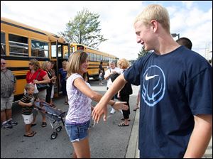 Jordyn Taylor, 13, and Benjamin Swartz, 15, greet each other before boarding a bus for a shopping spree for young tornado victims at JC penny and Aeropostale at the Shops at Fallen Timbers.