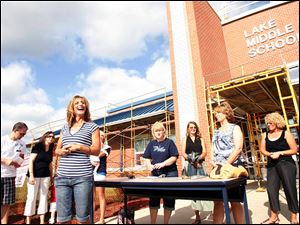 Wearing stripes at left, Diane Witt, wife of Lake Local Superintendent Jim Witt, urges shopping spree participants to board buses and get on their way to replacing damaged clothing.