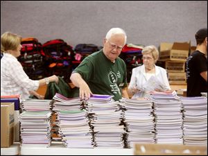 Ernie Brown stacks notebooks while others in the background move more supplies.