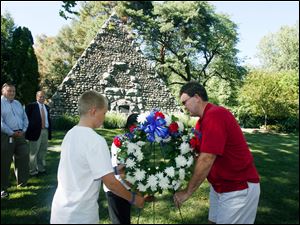 Slug: CTY service19p a  The Blade/Jeremy Wadsworth  Caption:  Left t right Ted Long and David Wehrmeister watch as Isaac Holley, 12, Nikki Mayes, 13, and Jay Gast lay a wreath during a dedication ceremony at the grave site of John Gunckel, founder of the Newsboys Association in 1892, in the Historical Woodlawn Cemetery Wednesday, 08/18/10, in Toledo, Ohio. The Old Newsboys was founded after John Gunckel noticed the rowdy  behavior of the young boys who sold newspapers in the streets of  downtown Toledo. He felt if given a little help, these boys could  develop the "other half" and become productive citizens. On December 25, 1892, Gunckel invited 102 of these "ruffians" to a Christmas dinner. With the support of local newspapers and several prominent businessmen, he helped the boys organize the Toledo Newsboys' Association. It was the first of its kind in the U.S. He established a national Newsboys organization in 1904 at the St. Louis World's Fair. The newsboys evolved into the Boys Club in 1942 and later, The Boys and Girls Club in 1982. The Old Newsboys Good fellow Association also evolved from Gunkel's work. Gunckel died on Aug. 16, 1915, eleven years to the day that the national organization was established. In tribute, the newsboys built a 30' x 26' stone pyramid on his grave. Overlooking a stream a half-mile from the  main entrance, the 1,000-ton pyramid stands twenty-six feet tall. It is  made of approximately 10,000 small stones and rocks from all over the  world, including agates from the Holy Land and rare stones from China, Japan, and Alaska that Toledo citizens contributed.