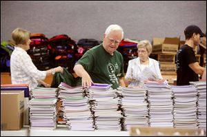 Ernie Brown stacks notebooks while others in the background move more supplies.