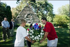 Slug: CTY service19p a  The Blade/Jeremy Wadsworth  Caption:  Left t right Ted Long and David Wehrmeister watch as Isaac Holley, 12, Nikki Mayes, 13, and Jay Gast lay a wreath during a dedication ceremony at the grave site of John Gunckel, founder of the Newsboys Association in 1892, in the Historical Woodlawn Cemetery Wednesday, 08/18/10, in Toledo, Ohio. The Old Newsboys was founded after John Gunckel noticed the rowdy  behavior of the young boys who sold newspapers in the streets of  downtown Toledo. He felt if given a little help, these boys could  develop the 