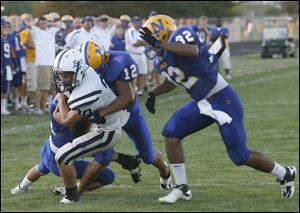 Lakota's Logan Greiner is tackled by Northwood's Ricky Hartley as Mike Prothero moves in to help.
