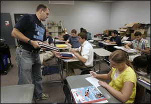 French teacher Jeff Lake distributes textbooks during the first day of school for sophomores, juniors, and seniors in their temporary quarters in Northwood. 
