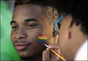 Kilo Smith, 18, of Toledo has a rainbow flag painted on his face by Shannon Frye.
