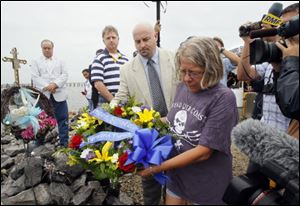 St. Bernard Parish President Craig Taffaro, center, carries a wreath with Diane Phillips to the edge of the Mississippi River Gulf Outlet during a memorial service