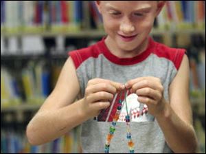 Zach Murdock, 6, of Petersburg puts the finishing touches on a necklace.  
