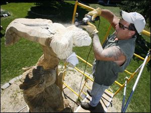 Steve Gore, who was severely beaten in an attack near Woodville last year, carves a wildlife sculpture in the front yard of his home in Temperance.