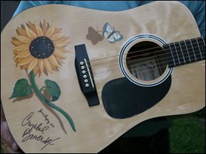 Local artist Jenni Freytag painted sunflowers and butterflies on the guitar that Crystal Bowersox autographed for The Butterfly House.