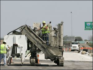 Foreman Steven Risner, left, and Eric Miller prepare a concrete-pouring machine at the Maumee project.