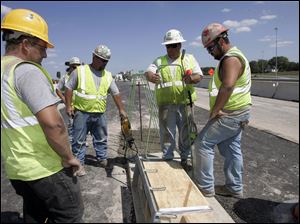 Foreman Steven Risner, second from right, confers with masonry crew members Mark Maddy, left, Steve Williams, and Donny Williams as the work on replacing the deck on  the State Rt. 24 bridge over I-475 in Maumee.