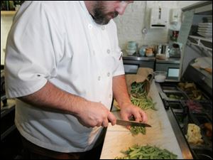 Chef Michael Bulkowski cuts green beans for a halibut dish at his Findlay restaurant, Revolver.