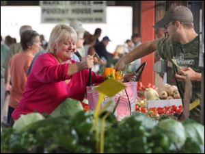 Pam Weirauch, owner of Pam's Corner on 10th Street in Toledo, buys sweet peppers from Ed Farnsel of Metamora, Ohio, at the Farmers' Market downtown.