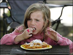 Raegan Beverly, 6, of Defiance tastes a funnel cake at the fair. Like most area fairs, the Fulton County's has a plethora of sweet and fried food offerings. Local organizations as well as carnival stands are big draws.