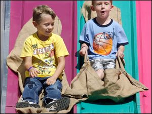 Joshua Emerling, left, and Calib Brashear, both 5-year-olds from Defiance, take a ride down the big slide.