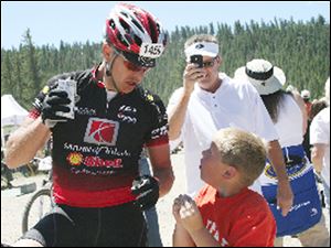 Matt Thourot of Maumme stops for some refreshment and a chat with his son, Dekker, at the Leadville Trail 100 mountain bike race.