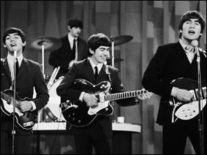 The Beatles - Paul McCartney, Ringo Starr, George Harrison, and John Lennon -perform on the 'Ed Sullivan Show' in 1964.