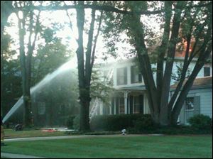 A firefighter douses flames that can be seen shooting from the roof of this home at 566 Front St. in Perrysburg.