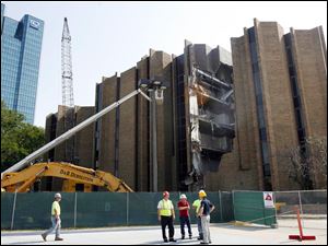 Demolition crews stand outside the old United Way Building downtown as work that is to end in early October breaks exterior walls.
