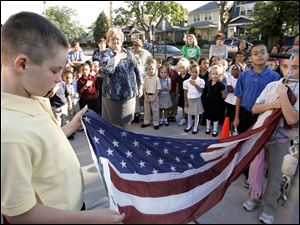 CTY remember11p  9/10/10  The Blade/Dave Zapotosky John Martis, 11, left, and Charlene Palmer, 11, right, raise the U.S. flag as students and staff at Navarre Elementary School in East Toledo hold a brief ceremony to remember the terrorist attacks of September 11, 2001, Friday September 10, 2010.  Both are sixth grade students. A moment of silence was observed and essays were read by two sixth grade students, Paul Espino, and Locadio Ruiz. Summary:  9/11 observation at Navarre Elementary School.