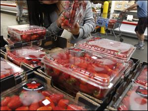 A Costco customer checks strawberries at a store in California.