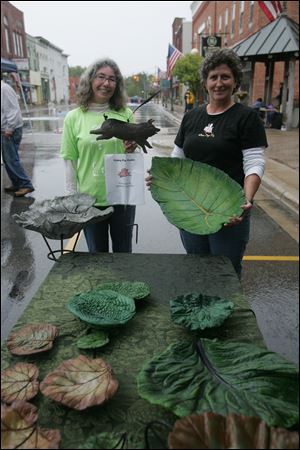 NBRN art15p   The Blade/Lori King  09/11/2010  Flying Pig Studio artists Carol Glauner, left, and Katie Maves show off their cement leave sculptures during the Art at you Feet show in Blissfield, Michigan. The art fair ended early Saturday due to rain.