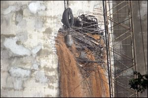 SMoldering wheat pours out of holes that a wrecking ball punched into the Miami Street grain silo