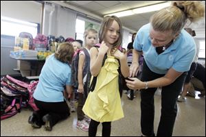Slug : NBRE backpacks09p  Date:  09092010        The Blade/Andy Morrison       Location: Rossford   Caption:  Kindergartner Audrey Miller gets help putting on a backpack to model from Kay Koevenig, chair of the Backpack to the Future Program at Glenwood Elementary, Thursday, 09092010.    The supplies were donated by members of the Owens Community College Alumni Association. Summary:  EDS. supplies were not passed out today. This was a staged media event basically.