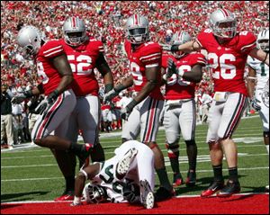Ohio running back Vince Davidson lies in the end zone after being tackled by Cameron Heyward for a safety as Buckeyes defenders celebrate.