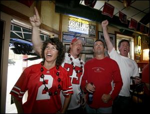 Melisa and Mike Konczal of Chesterfi eld, Mich., Chad Garrison of Maumee, and Mark Kramer of Perrysburg cheer on the Buckeyes at Dale's Bar on Sept. 11.