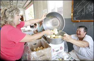 Connie Bachman, left, and Helen Dyke share a laugh and a bowl full of apples as volunteers fill the Grand Rapids fire station to prepare the fruit for the process that eventually will result in apple butter for its namesake festival.