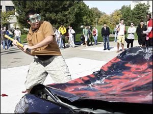 Slug: CTY peprally01p                               9/30/2010 The Blade/Amy E. Voigt                  Toledo, Ohio  CAPTION:  Osama Nazzal, a senior from Toledo, takes a whack at a donated Towncar from ABC Auto Parts, during the traditional car  smashing at a pep rally at the Student Union to get students and staff excited before the Rockets homecoming game this Saturday against the Wyoming Cowboys.